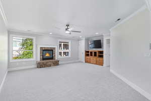 Unfurnished living room featuring ornamental molding, light colored carpet, a fireplace, a ceiling fan, and recessed lighting
