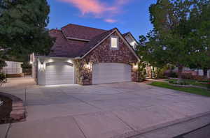 View of front facade with stone siding, driveway, a tile roof, and an attached garage