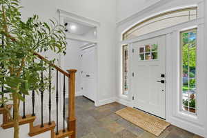 Entryway with healthy amount of natural light, stone tile flooring, and stairway
