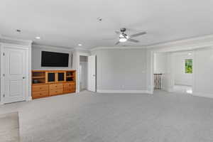 Unfurnished living room featuring light carpet, ornamental molding, recessed lighting, and ceiling fan