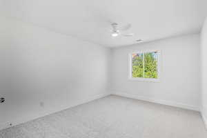Spare room featuring light carpet and ceiling fan
