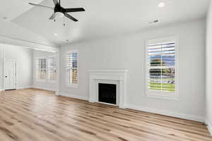 Unfurnished living room with a brick fireplace, a ceiling fan, light wood finished floors, vaulted ceiling, and recessed lighting
