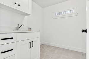 Washroom featuring cabinet space, hookup for a washing machine, and light tile patterned floors