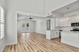 Kitchen featuring white cabinets, backsplash, french doors, stainless steel appliances, and ceiling fan