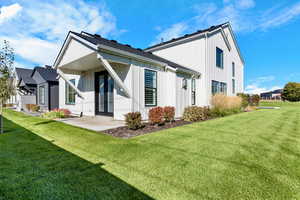 Back of property featuring board and batten siding, a lawn, and roof with shingles