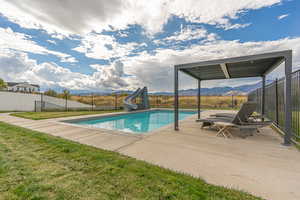Heated saltwater pool with Baja shelf, cyclone slide, concrete pool deck, and wrought-iron fence for added safety.