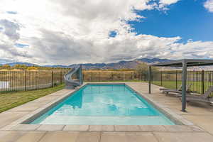 Heated saltwater pool with Baja shelf, cyclone slide, concrete pool deck, and wrought-iron fence for added safety.
