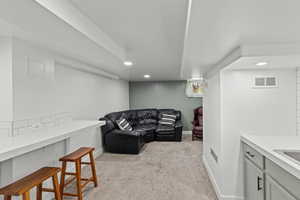 Living area with light carpet and recessed lighting