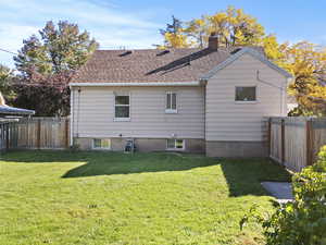 Back of house with a fenced backyard and a chimney