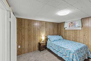 Bedroom featuring wood walls and carpet floors