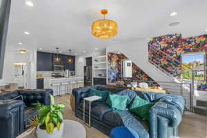 Living room featuring light wood-style flooring, recessed lighting, stairs, and a chandelier