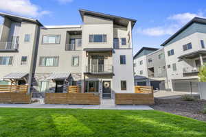 Rear view of property featuring a balcony, a fenced front yard, stucco siding, and a gate