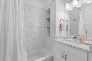 Full Bathroom with shower / tub combo and vanity with custom tile and shelving