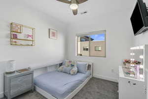 Carpeted bedroom with ceiling fan and blackout roller shades