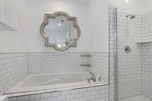 Primary bathroom featuring large soaker tub and separate shower with custom tile.