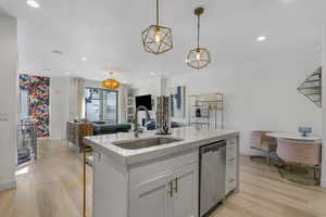 Kitchen with light stone countertops, light wood finished floors, open floor plan, dishwasher, and recessed lighting