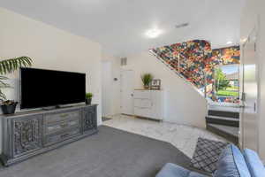 Living room or office space with stairs, light tile flooring, and carpet