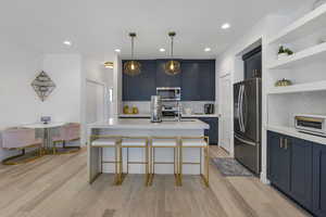 Kitchen with blue cabinetry, open shelves, stainless steel appliances, tasteful backsplash, and recessed lighting