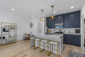 Kitchen with blue cabinetry, tasteful backsplash, a kitchen bar, light wood-type flooring, and recessed lighting