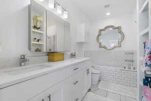 Primary bath featuring a garden tub, double vanity, a tile shower, and tile floors