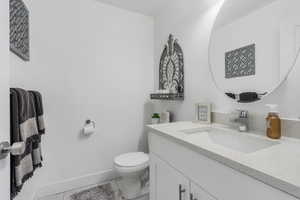 Half bath by garage featuring vanity, medicine cabinet and light tile flooring