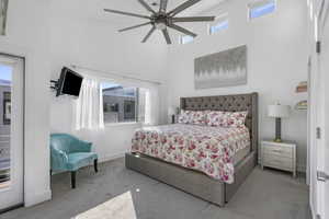 Primary bedroom with great natural lighting and vaulted ceilings.  Has solar powered upper window coverings, carpet flooring, and a ceiling fan