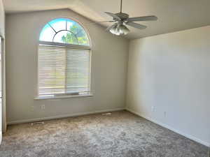 Carpeted empty room with lofted ceiling and ceiling fan