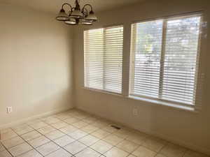 Unfurnished dining area with light tile patterned floors and a chandelier
