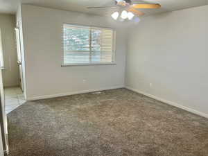Unfurnished room featuring light carpet, ceiling fan, and light tile patterned floors