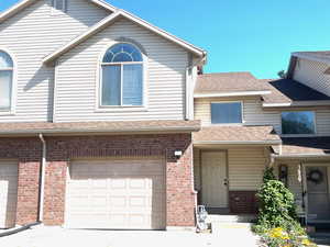 Traditional-style home with roof with shingles, brick siding, and driveway
