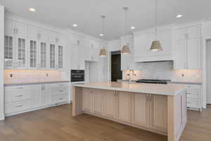 Kitchen featuring tasteful backsplash, glass insert cabinets, dark wood-style floors, white cabinets, and recessed lighting