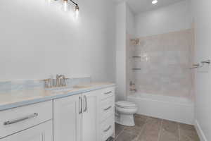 Bathroom featuring vanity, shower / bath combination, and light tile patterned floors