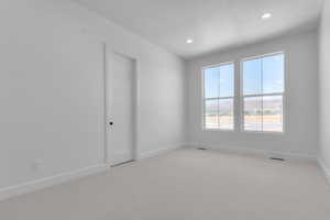 Empty room with light colored carpet, recessed lighting, and a textured ceiling