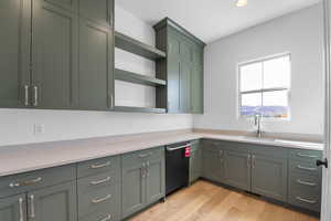 Kitchen featuring open shelves, green cabinetry, light wood-style flooring, dishwashing machine, and recessed lighting