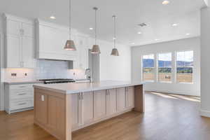 Kitchen featuring a mountain view, backsplash, white cabinetry, a kitchen island with sink, and recessed lighting