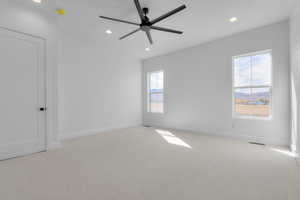 Empty room featuring light carpet, recessed lighting, a ceiling fan, and a mountain view