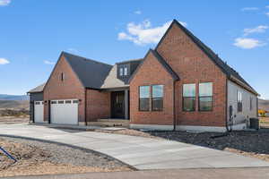 View of front facade featuring brick siding, concrete driveway, a shingled roof, and a mountain view