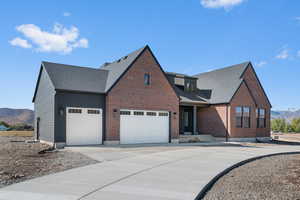 View of front of house with a mountain view, driveway, brick siding, and an attached garage