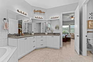 Bathroom with double vanity, light tile patterned floors, a bath, and connected bathroom