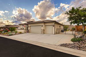 Mediterranean / spanish home featuring a garage, concrete driveway, stucco siding, stone siding, and a gate