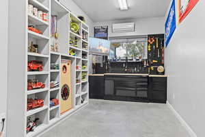 Bar area with a workshop area, concrete floors, a wall unit AC, and a textured ceiling