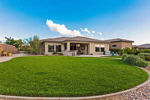 Rear view of property with stucco siding, a tile roof, a yard, and a patio area