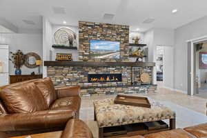 Living area featuring a stone fireplace, tile patterned flooring, and recessed lighting