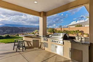 Fenced backyard with an outdoor kitchen, a patio, and a mountain view