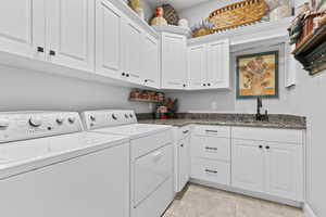 Washroom with independent washer and dryer, cabinet space, and light tile patterned floors