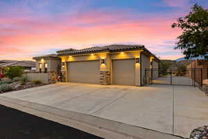 View of front of house with an attached garage, a gate, driveway, and stucco siding