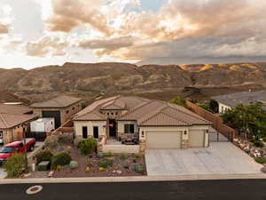 View of front of property featuring driveway, an attached garage, stone siding, and a mountain view