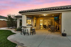 Patio terrace at dusk with a patio and area for grilling