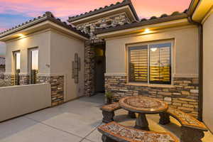 Property entrance with stone siding, a patio area, and stucco siding