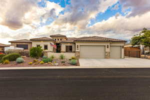 Mediterranean / spanish-style home with stucco siding, a garage, stone siding, and concrete driveway